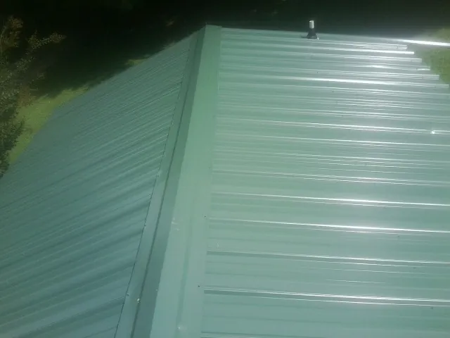 New green metal panels meeting at the ridge of a roof — Flat Roof Repair work by our crew in Battle Ground