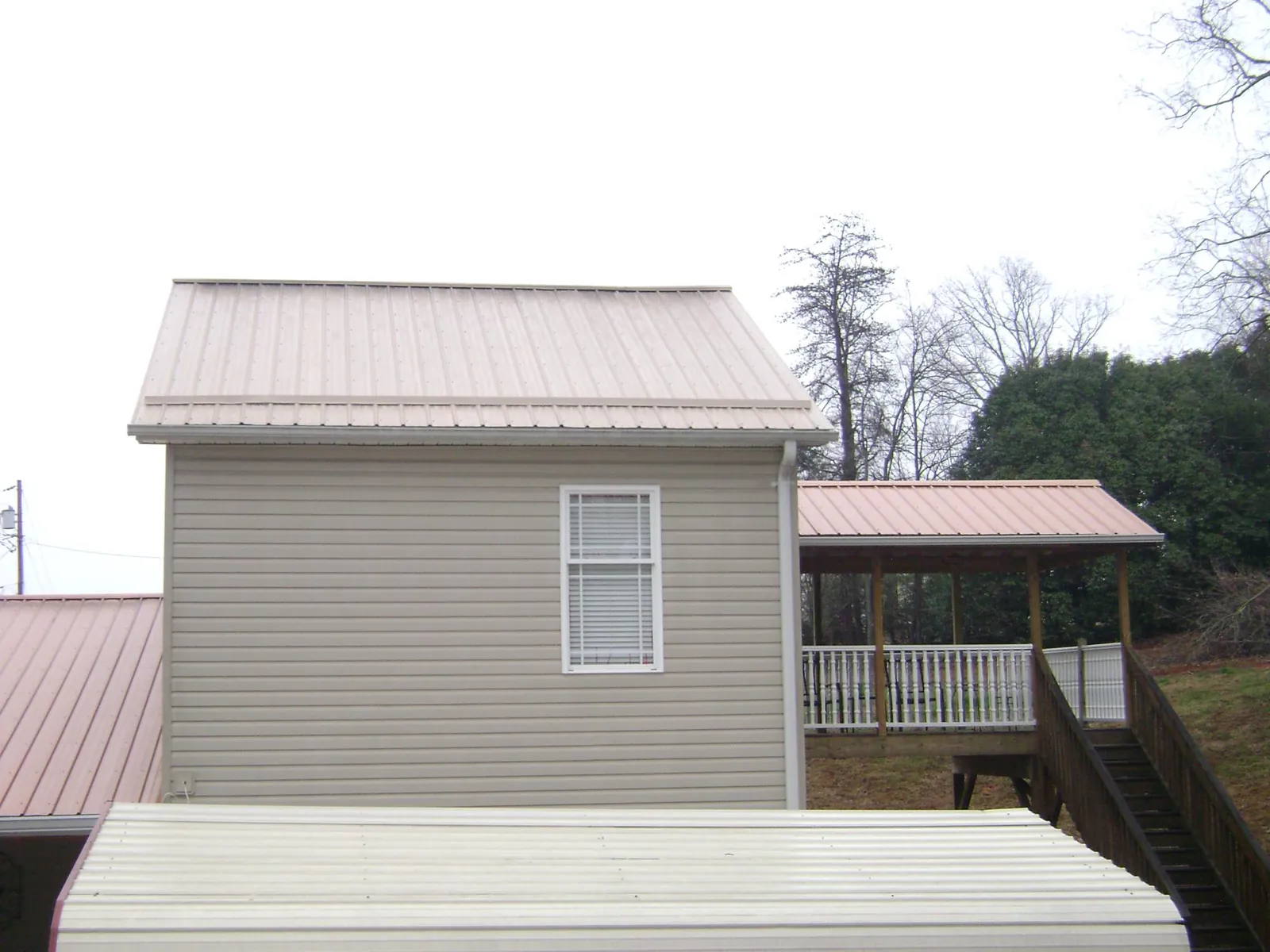 Tan metal roofs on a two story addition and attached porch, from a Roof Replacement job in Battle Ground
